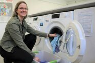 Junge Frau belädt eine Waschmaschine mit Wäsche