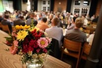 Ein voller Saal mit einem Blumenstrauß im Vordergrund