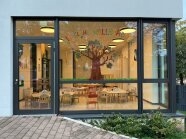 Eingangsbereich Krippenhaus "Die kleinen Wallstädter": Gläserne Eingangsfront, dahinter beleuchteter Raum