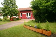 Außenansicht eines Gebäudes, davor Büsche und Bäume