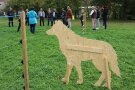 Ein hölzerner Wolf steht vor einem Zaun